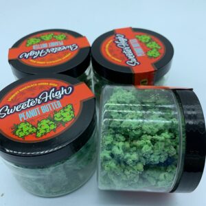 A jar of Sweeter High weed strain with vibrant buds, showcasing a balanced, sweet, and earthy aroma.