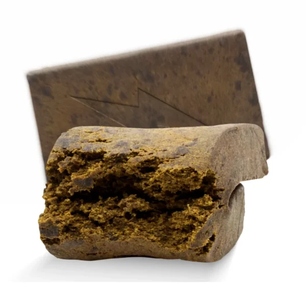 Dark brown, pliable Afghan Hash concentrate with earthy texture, displayed in a glass jar on a rustic wooden surface.